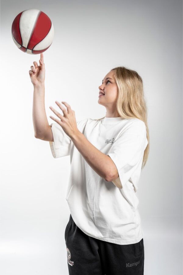 Game Day Heavy Tee side – Seitenansicht des Models, wie sie einen Basketball auf ihrem Finger dreht